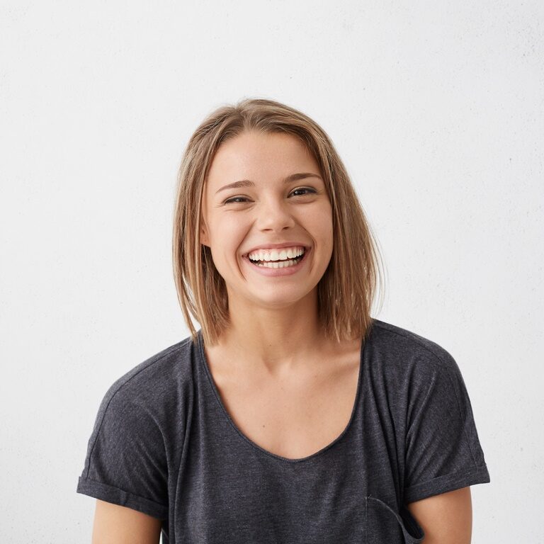 Attractive woman with short fair hair being very glad smiling with broad smile showing her perfect teeth having fun indoors. Joyful excited cheery femlae rejoicing after being proposed to marry